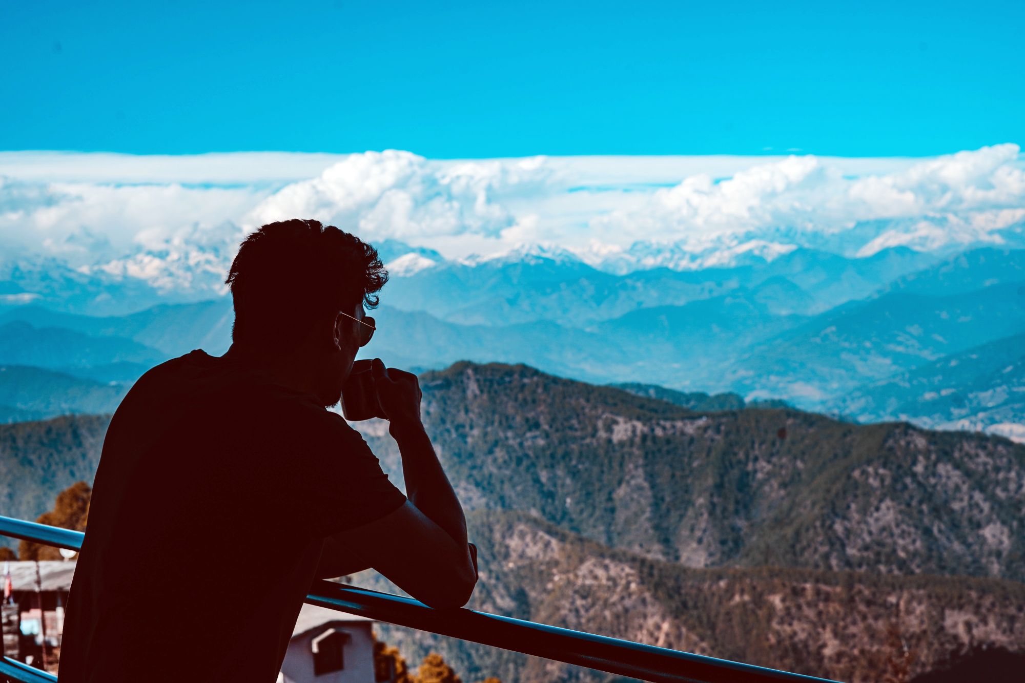 Man drinking from a bamboo cup while looking at a mountain