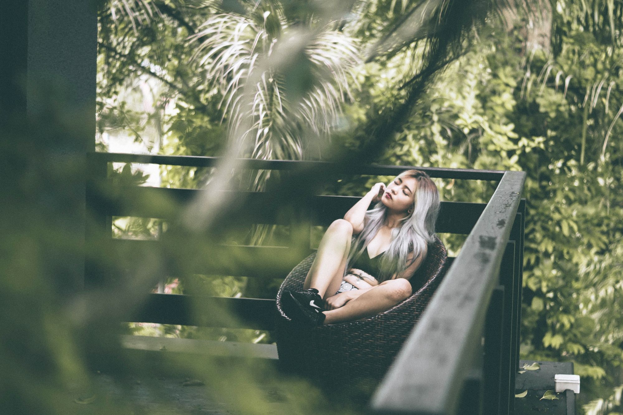 Woman relaxing in chair on outdoor bamboo decking among trees